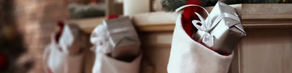 Three Christmas stockings hanging on a decorated fireplace